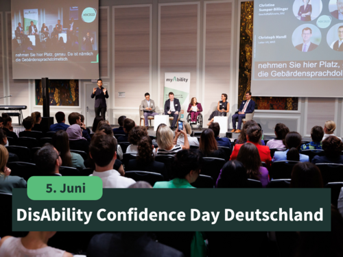 5. Juni: DisAbility Confidence Day Deutschland, Bühne mit Speaker:innen und Moderatorin, das Publikum im Vordergrund
