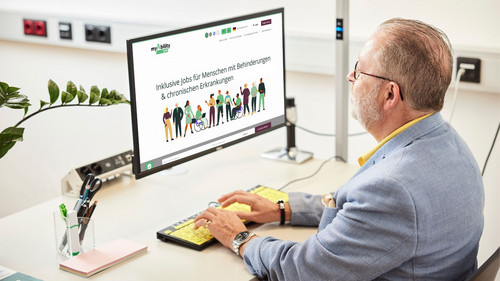 Person sitzt vor einem Computer. Auf dem Bildschirm ist die Website myAbility.jobs mit der Überschrift "Inklusive Jobs für Menschen mit Behinderungen & chronischen Erkrankungen" zu sehen und eine Grafik von Menschen mit und ohne Behinderungen.