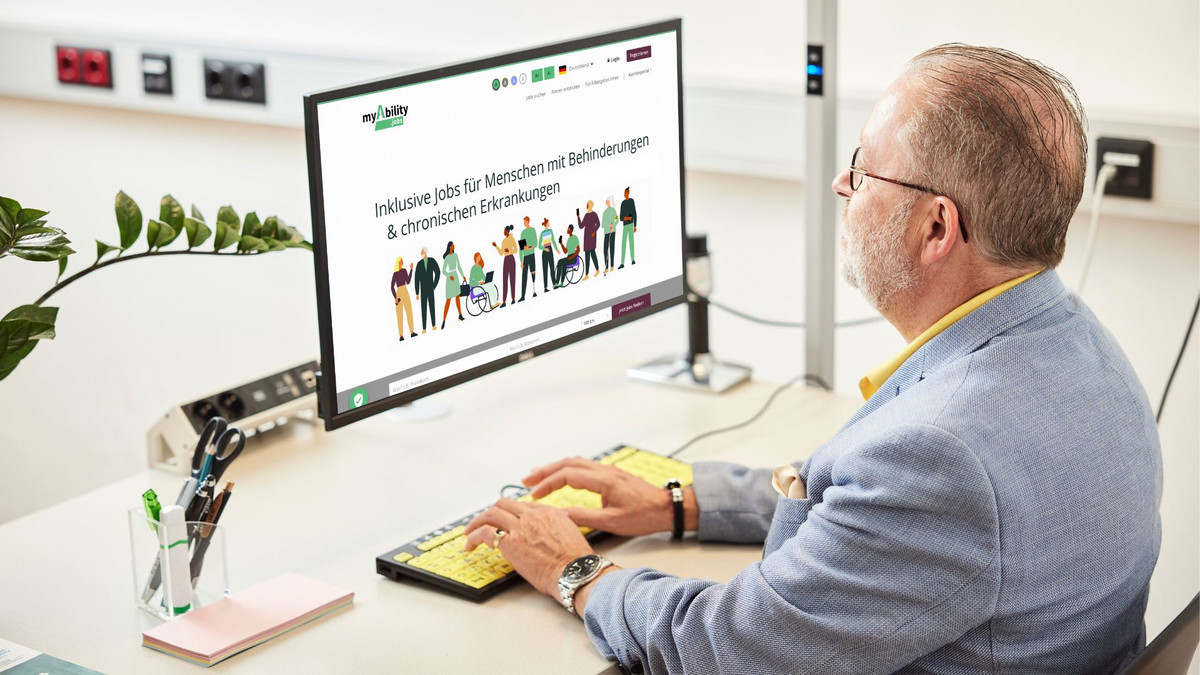 Person sitzt vor einem Computer. Auf dem Bildschirm ist die Website myAbility.jobs mit der Überschrift "Inklusive Jobs für Menschen mit Behinderungen & chronischen Erkrankungen" zu sehen und eine Grafik von Menschen mit und ohne Behinderungen.
