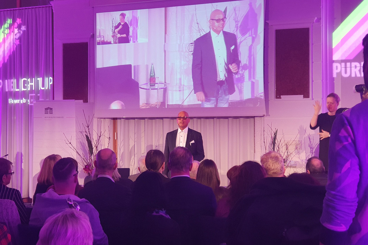 Parlamentsveranstaltung. Lila beleuchtete Bühne. Saliya Kahawatte hält Keynote.
