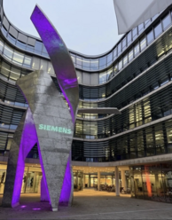 Lila beleuchtete Skulptur vor einem Siemens Gebäude.