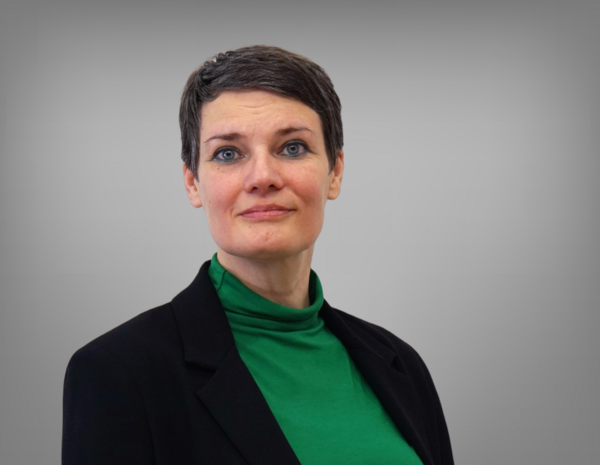 Portrait von Elisabeth Prinz. Sie hat kurze graue Haare und trägt ein grünes Rollkragen T-Shirt mit einem schwarzem Blazer.