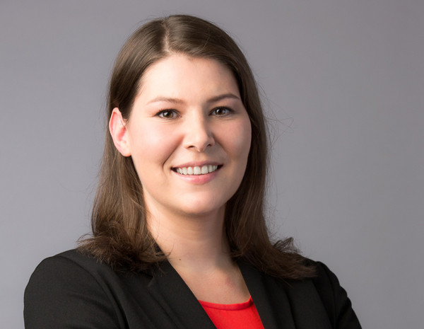 Portrait von Beora Gogulka, weiblich gelesene Person mit schulterlangem braunem Haar und schwarzem Blazer