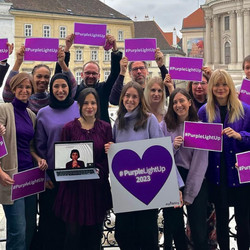 Das Team von currycom, die Schilder mit der Aufschrift "#PurpleLightUp 2023" hochhalten. Die Kleidung und Schilder sind in verschiedenen Lilatönen gehalten