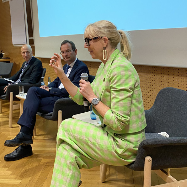 Martin Kocher, Erich Lehner, Caroline Casey spricht mit Mikrofon zum Publikum