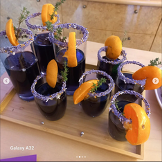 Mehrere Gläser mit lila Getränken. Orangenscheiben als Garnitur
