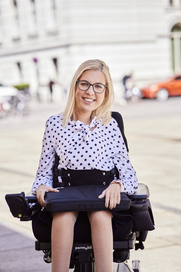Young woman sitting in a wheelchair and smiling at the camera