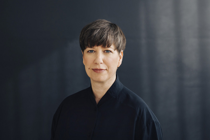 Porträt von Nora Biz mit schwarzer Bluse, dunkelbraunen kurzen Haaren.