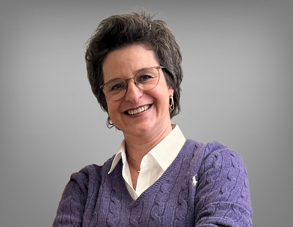 Portrait von Stefanie Kirwald, weiblich gelesene Person mit kurzem braunem Harr und einer Brille. Sie trägt ein weißes Hemd mit einem lila Pullover.