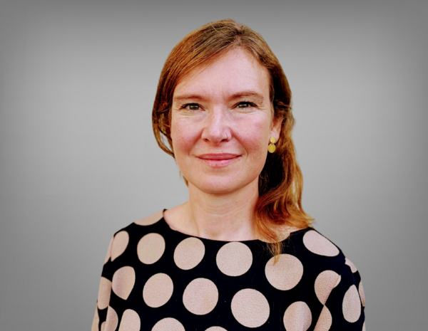 Portrait von Katharina Thill, sie hat schulterlange braune Haare und trägt ein schwarzes T-Shirt mit weißen Kreisen darauf.