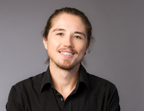 Portrait von Dominik Moser, männlich gelesene Person mit blondem Haar und schwarzem Hemd