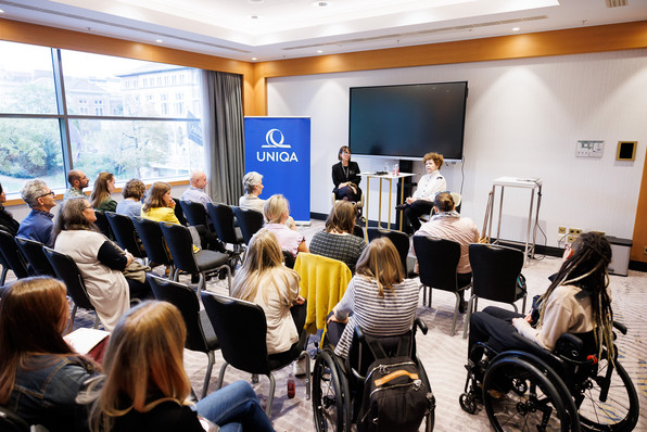 Mehrere Personen sitzen im Workshopraum "UNIQA", 2 Frauen sprechen vorne.