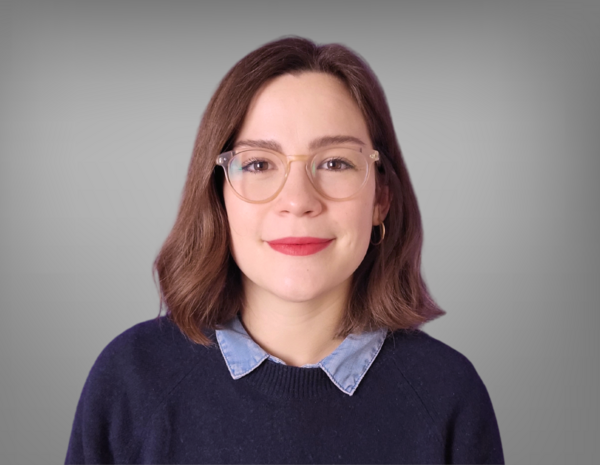 Portrait of Anna Herzog, female person with brown shoulder-length hair and glasses. She is wearing a dark blue sweater.