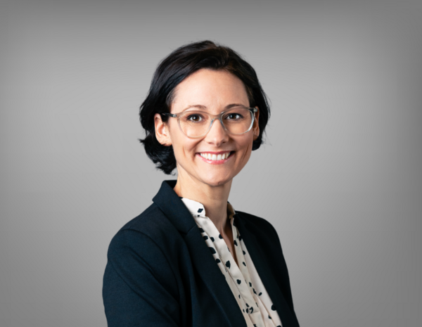 Portrait von Bettina Hillebrand, weiblich gelesene Person mit schulterlangem braunem Haar und weißem Blazer