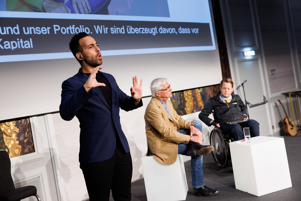 Charly Kleissner und Gregor Demblin auf der Bühne des DCD. Gebärdensprachdolmetscher im Vordergrund.