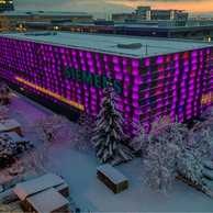 Ein Siemens-Gebäude in der Schweiz, beleuchtet in Lila, mit Schnee bedeckte Bäume im Vordergrund.