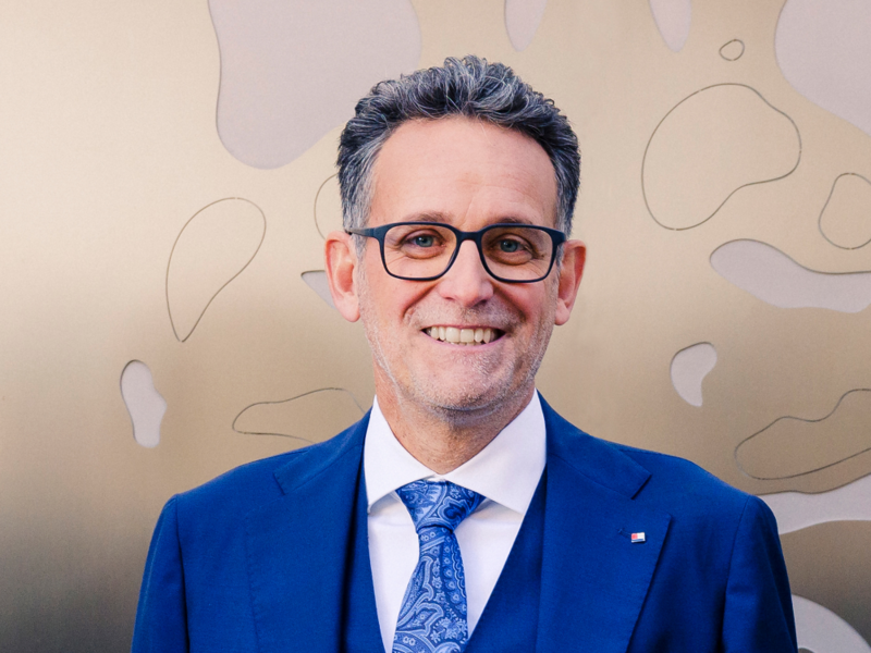 Portraitfoto von Gerhard Burtscher, im blauen Anzug einer Brille