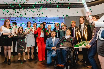 myAbility team celebrates 10 years of myAbility. Green confetti fly through the air.