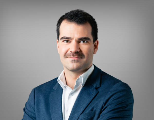 Portrait of Andreas Maierhofer, male person with short brown hair and beard in white shirt and gray jacket