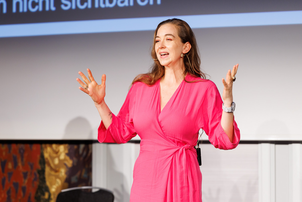 Frau in pinken Overall hält Keynote auf der Bühne