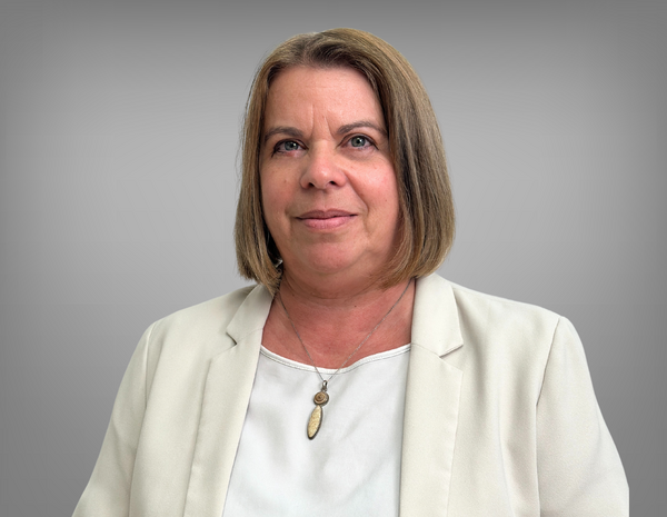 Portrait von Ulrike Papstein. Sie hat kurze hellbraune und trägt ein weißes T-Shirt mit einem weißen Blazer.