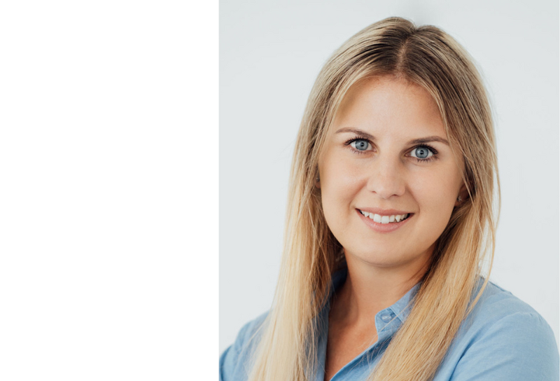 Die Person hat lange blonde Haare und trägt eine blaue Bluse.