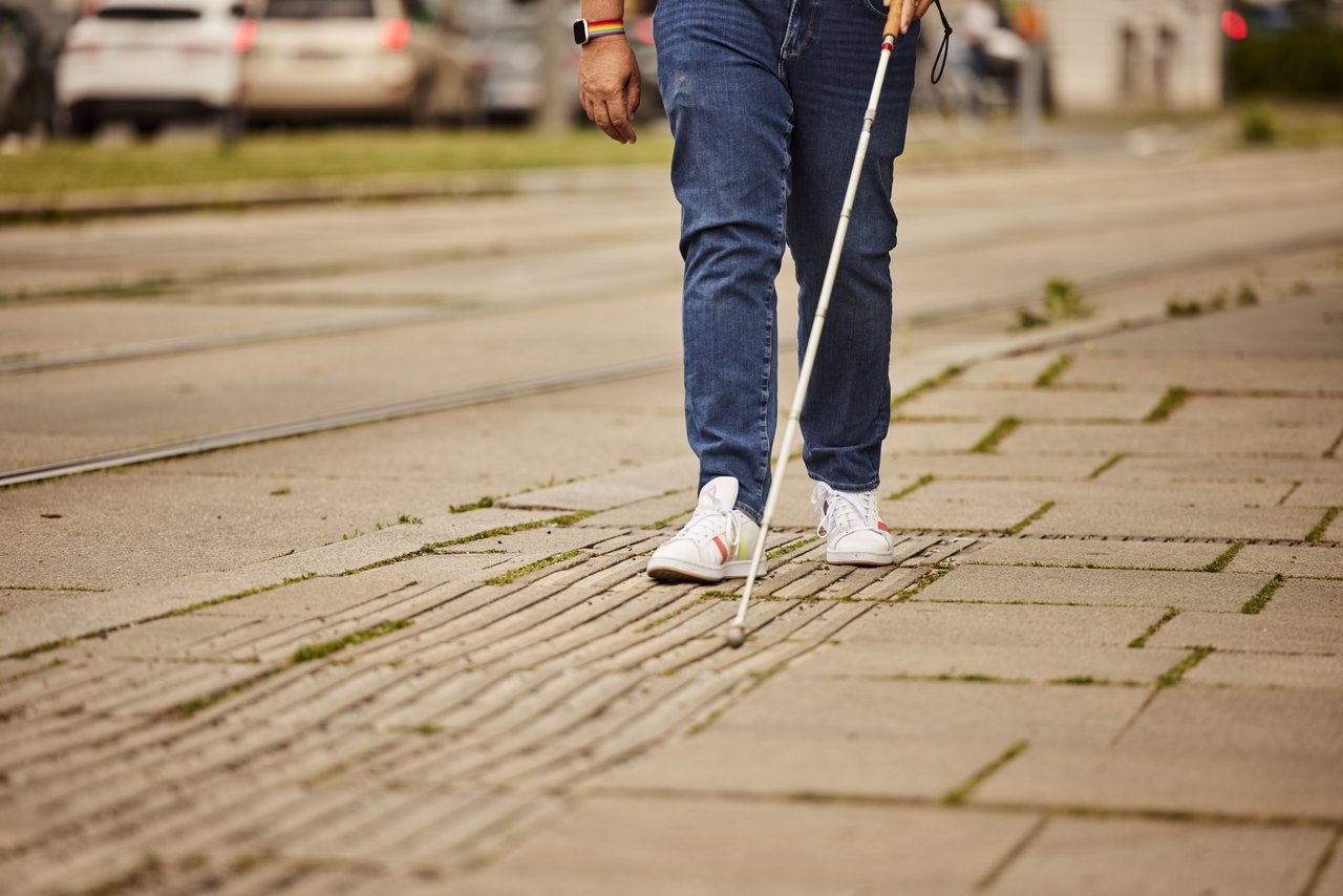 Street on which someone walks with a white cane