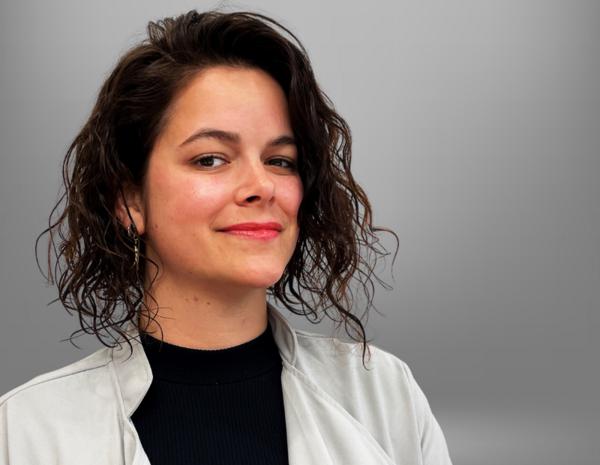 Portrait von Viviane Martin, weiblich gelesene Person mit halblangem lockigen Haar und schwarzem Rollkragenpullover
