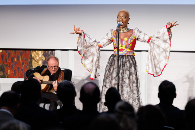 Musikalische Darbietung auf der Bühne. Schwarze Frau mit farbenfrohen Kleid singt. 