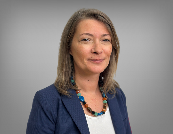Portrait von Nina Putzenlechner. Nina hat schulterlanges hellbraunes Haar und trägt eine Kette. Sie trägt ein weißes T-Shirt mit blauem Blazer.