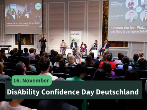 16. November: DisAbility Confidence Day Deutschland, Bühne mit Speaker:innen und Moderatorin, das Publikum im Vordergrund