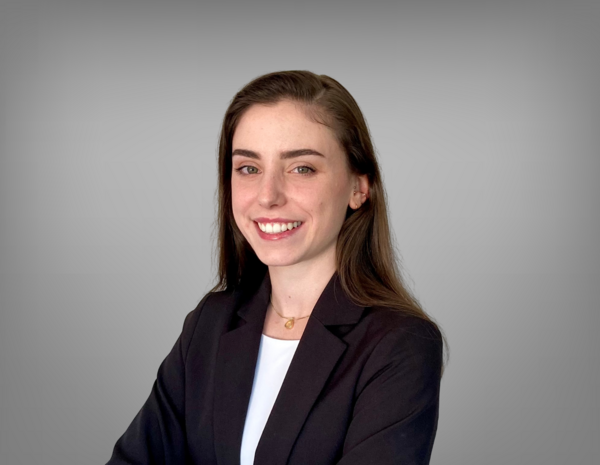 Portrait von Antonia Cichocki. Sie hat lange dunkelbraune Haare und trägt ein weißes T-Shirt mit einem schwarzem Blazer.