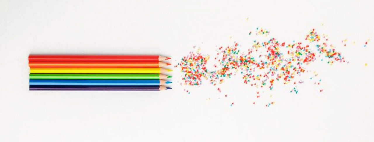 Verschieden färbige Buntstifte in einer Reihe. Daneben die Reste vom Anspitzen der Stifte. 