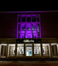 Lila beleuchtetes Gebäude bei Nacht. Über dem Eingang "Gilette"