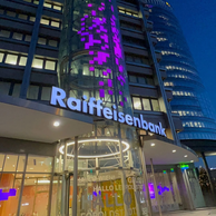 Hochhaus mit lila Lichtinstallation von unten fotografiert. Raiffeisenbank