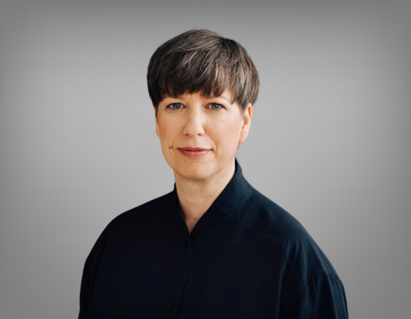 Portrait von Nora Bilz, sie trägt kurzes braunes Haar. Nora trägt ein schwarzes Hemd.